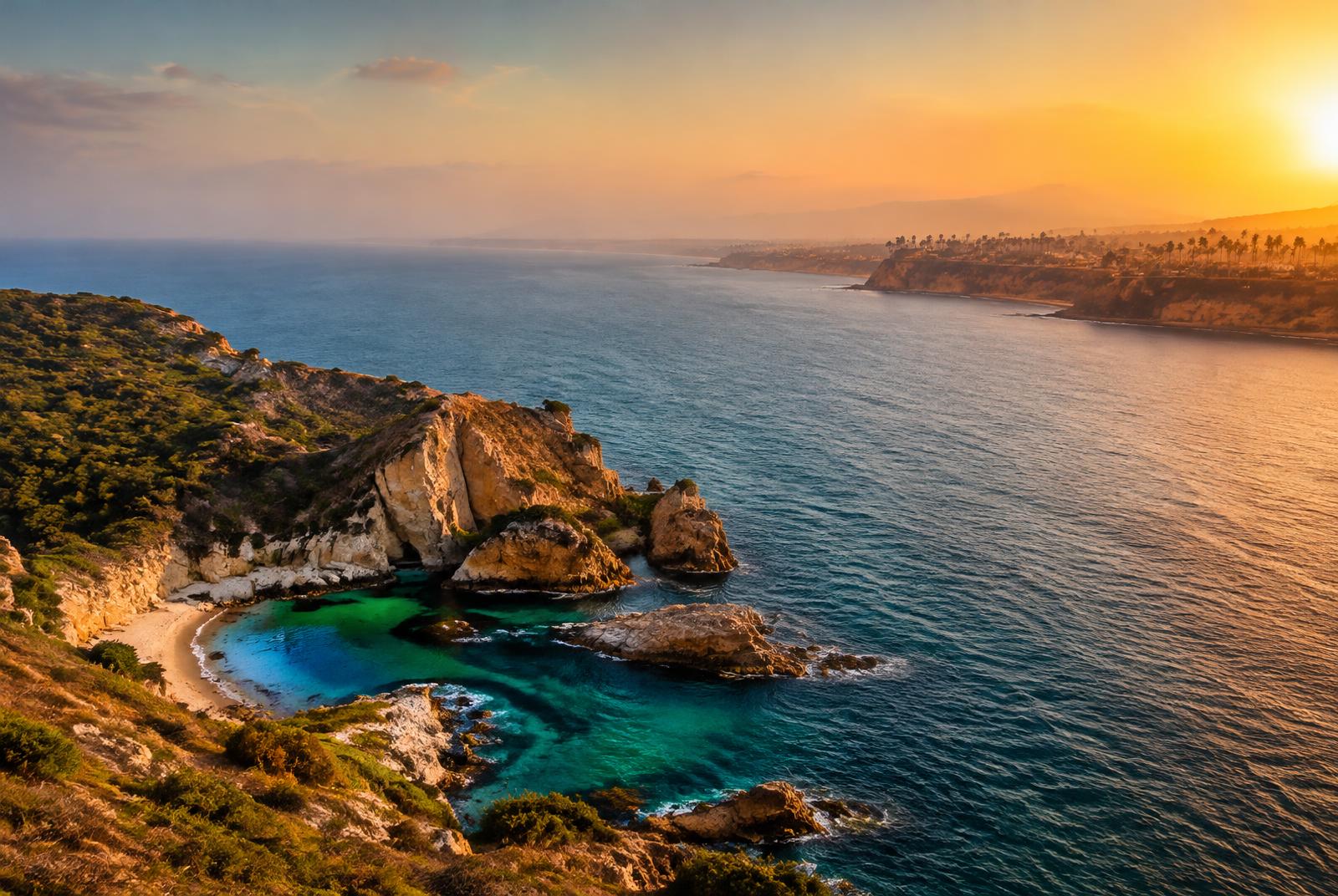 A rugged Mediterranean coastline facing a palm-lined Pacific shore at sunset